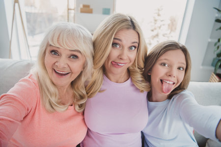 Photo portrait of different generations women taking selfie grimacing fooling showing tongues at...