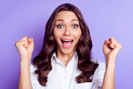 Photo of cheerful charming lady open mouth raise fists wear white shirt isolated violet color backgroundの写真素材