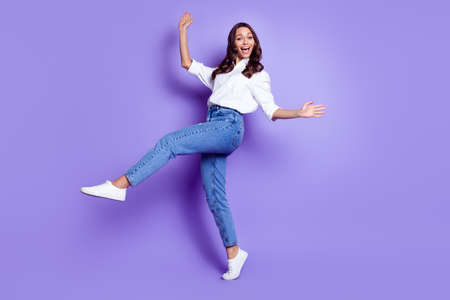 Photo of pretty excited lady dance have fun raise arm wear white shirt isolated purple color...