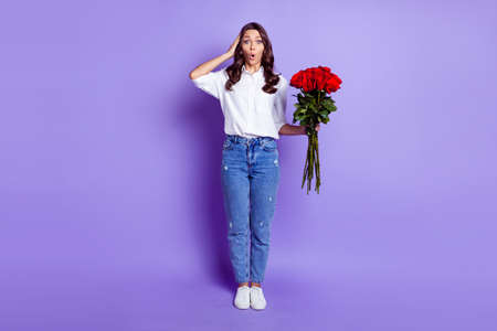 Photo of surprised crazy lady hold red roses open mouth wear white shirt isolated violet color...