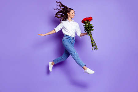 Profile photo of inspired lady jump hold bouquet go wear white shirt isolated violet color...