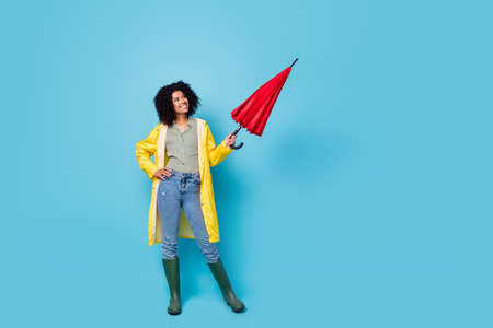 Full body photo of young cheerful woman happy smile wet raincoat look empty space isolated over blue...