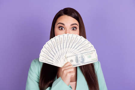 Photo of young funky funny businesswoman cover close mouth with money isolated on violet color backgroundの写真素材