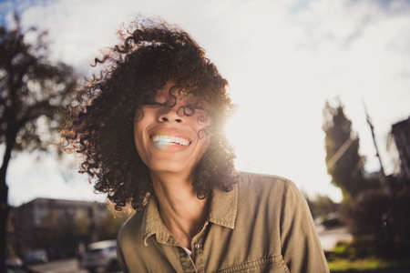 Portrait of adorable positive curly hairstyle dark skin lady beaming smile enjoy warm weather spend free time outdoorsの写真素材