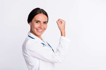 Photo of charming strong young lady physician dressed uniform rising fists smiling isolated white color backgroundの写真素材