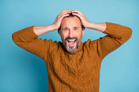 Photo portrait of middle-aged bearded man amazed shocked keeping head with hands shouting isolated...
