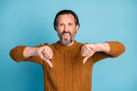 Portrait of unsatisfied person show two hands thumbs down look camera isolated on blue color...