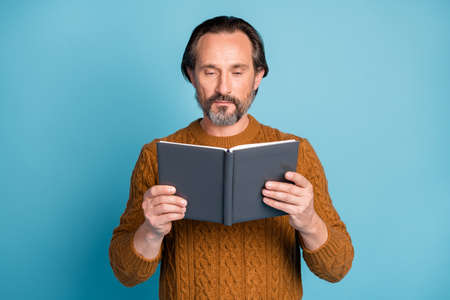 Photo portrait of serious professor reading book spending free time isolated on vibrant blue color backgroundの写真素材