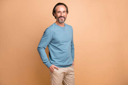 Photo portrait of man with hands in pockets isolated on pastel beige colored background