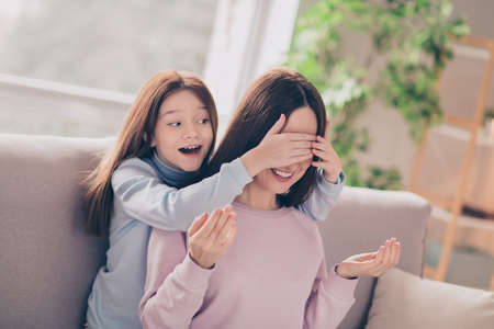 Photo of optimistic brunette red hairdo mom daughter hug play close eyes on sofa wear sweater at homeの写真素材