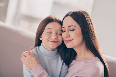 Photo of optimistic brunette red hairdo mom daughter hug sit on sofa wear sweater at homeの写真素材