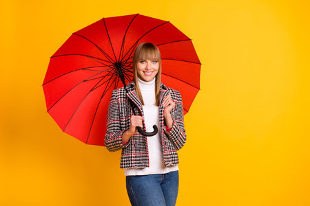 Photo of adorable person hand hold umbrella beaming smile look camera isolated on yellow color backgroundの写真素材