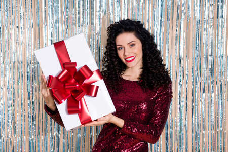 Photo of young charming attractive happy smiling positive girl hold christmas present isolated on glittered shiny backgroundの写真素材