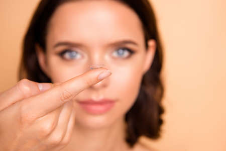 Close up photo beautiful amazing lady hands arms index finger hold show new contact lens advertise advice choice choose inserting eye blurry wear no clothes isolated beige pastel backgroundの写真素材