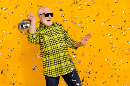 Photo of aged man happy positive smile clubber dance have fun disco ball party isolated over yellow...
