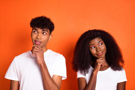 Photo of young happy thoughtful dreamy afro couple look copyspace thinking hold hand chin isolated on orange color backgroundの写真素材