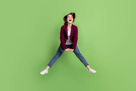 Full size photo of optimistic brown hairdo lady jump wear cardigan jeans sneakers isolated on green backgroundの写真素材