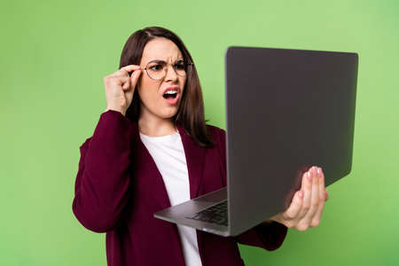Photo of sad brown hairdo lady hold laptop wear spectacles red cardigan isolated on green color backgroundの写真素材