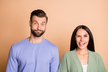 Photo of young smiling cheerful positive funky comic playful couple fooling isolated on beige color backgroundの写真素材