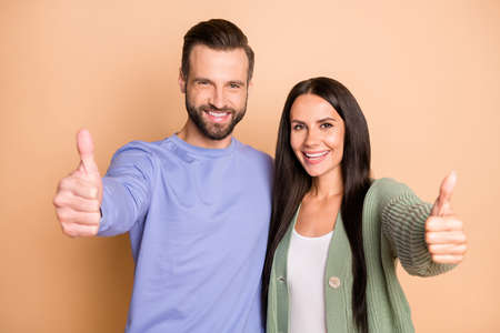 Photo of optimistic couple show thumb up wear sweater isolated on beige color backgroundの写真素材