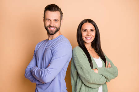 Back-to-back photo of young happy smiling cheerful couple of friends with crossed hands isolated on beige color backgroundの写真素材