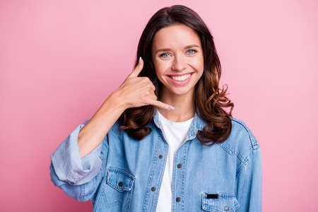 Photo of happy lovely woman make call me gesture charming smile wear denim jacket isolated on pink...