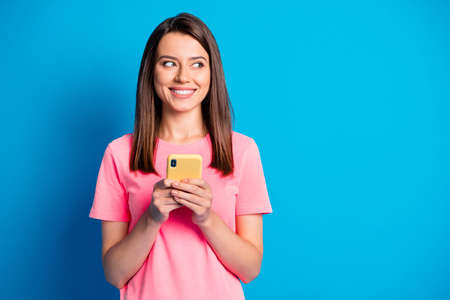 Photo portrait of curious brunette keeping cellphone smiling looking at blank space isolated on...