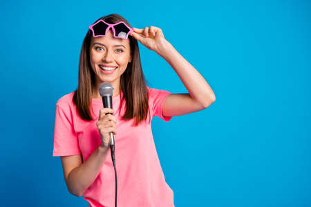 Photo portrait of smiling positive girl taking off star shaped sunglass keping mic on festival...