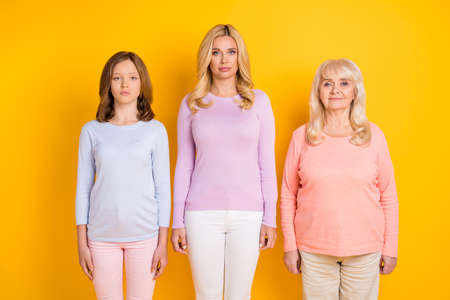 Photo of nice serious blond red hair grand mom daughter stand wear pastel cloth isolated on yellow color backgroundの写真素材