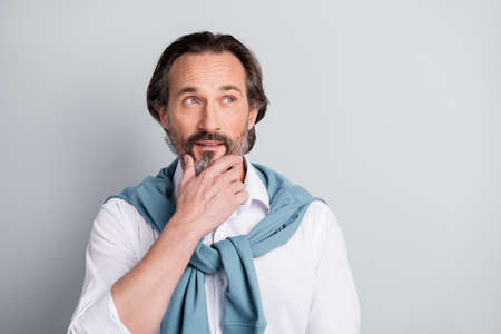 Portrait of positive person arm on chin look interested empty space thinking isolated on grey color backgroundの写真素材