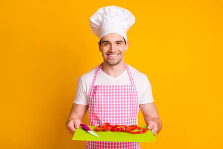 Photo of young happy excited smiling man chief in headwear hold board with chopped pepper isolated...