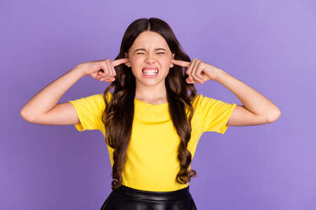 Portrait of nice stressed brunette hairdo girl cover ears wear yellow t-shirt isolated on vivid lilac color backgroundの写真素材