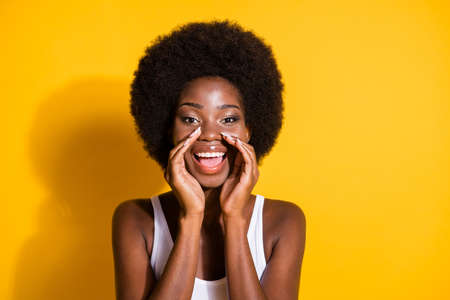 Photo of funky young girl look camera open mouth space palms shout wear white singlet isolated yellow color backgroundの写真素材