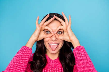 Photo of crazy funky happy woman fooling make finger glasses stick out tongue isolated on blue color backgroundの写真素材