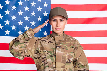 Portrait of calm serious lady arm head saluting greetings look focused camera isolated on usa national flagの写真素材