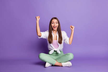 Photo portrait full body view of celebrating woman sitting in lotus pose isolated on vivid purple colored backgroundの写真素材