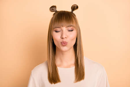 Photo of dreamy inspired cute lady pout lips blow air kiss close eyes wear t-shirt isolated beige color backgroundの写真素材