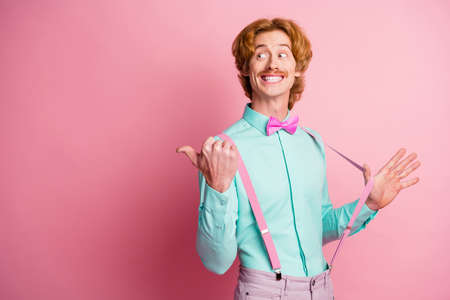 Photo of young happy smiling cheerful good mood man pull suspenders pointing thumb copyspace isolated on pink color backgroundの写真素材
