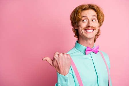 Portrait of young funky funny smiling cheerful excited positive man pointing finger copyspace isolated on pink color backgroundの写真素材