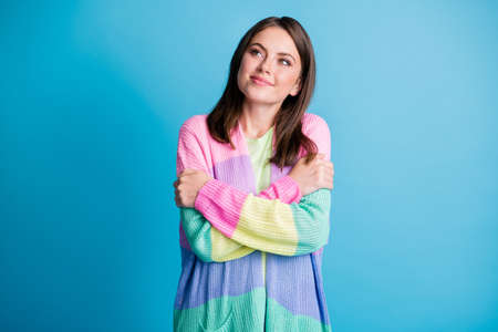 Photo of attractive happy dreamy young woman look empty space self hug isolated on blue color backgroundの写真素材