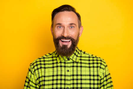 Portrait of attractive cheerful lucky man wearing checked shirt isolated over bright yellow color backgroundの写真素材
