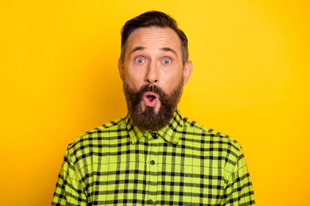 Photo of mature man brown hair beard amazed shocked surprised fake novelty news isolated over yellow color backgroundの写真素材