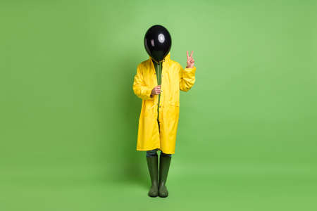 Full length photo of young man incognito cover face air balloon show peace cool v-sign isolated over green color backgroundの写真素材