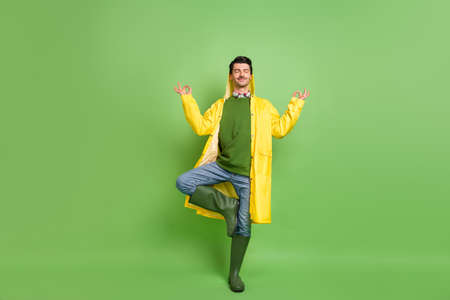 Full size photo of brunet optimistic guy do yoga wear cloak boots isolated on green color backgroundの写真素材