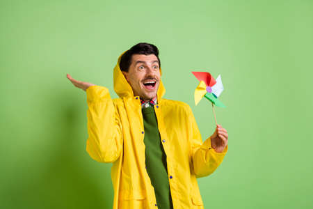 Photo of brunet impressed guy hold toy look empty space wear cloak isolated on green color backgroundの写真素材