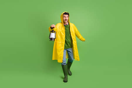 Full size photo of young happy excited funky funny man in raincoat go walk with lamp isolated on green color backgroundの写真素材