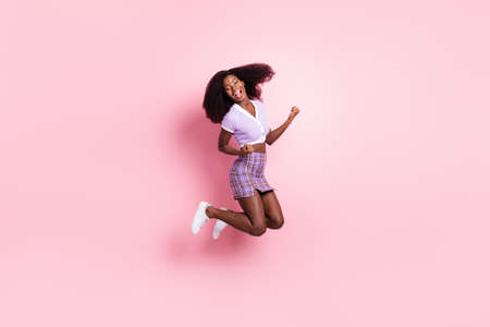 Full length body size view of pretty cool cheerful girl having fun jumping rejoicing isolated over pink pastel color backgroundの写真素材