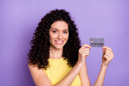 Portrait of pretty cheerful young girl arms hold banking card beaming smile isolated on purple color backgroundの写真素材