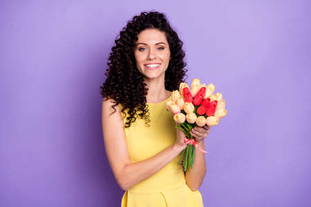 Portrait of gorgeous cheerful person hands hold flowers toothy smile look camera isolated on purple color backgroundの写真素材