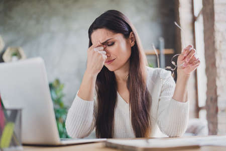 Photo of tired business lady sit table netbook take off specs close eyes wear white pullover in living room home indoorsの写真素材